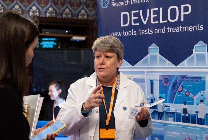 A scientist explains their science in front of a banner marked 'Develop'