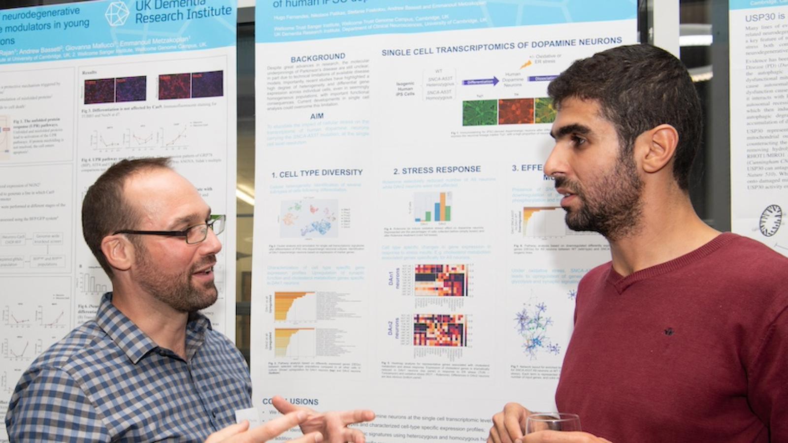 two people talk in front of a scientific poster